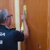 Un agente de la Policía Local de Elche precintando la casa en la que los detenidos tenían la actividad irregular de cuidado de personas dependientes.