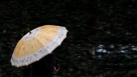 Una persona se protege de la lluvia con un paraguas. Una persona se protege de la lluvia con un paraguas.