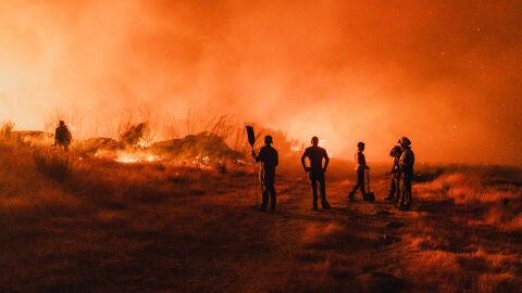 Bomberos y brigadistas forestales locales trabajan durante la noche para contener un incendio forestal que amenaza zonas residenciales en la parroquia de Bouses, ubicada en Oimbra, Ourense, Galicia, Espa&ntilde;a, el 19 de agosto de 2025. 