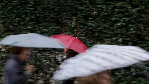Varias personas se protegen de la lluvia con un paraguas. Varias personas se protegen de la lluvia con un paraguas.
