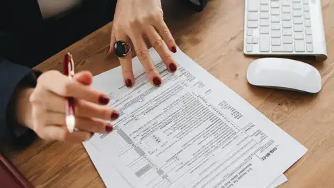 Una persona rellenando un documento para su presentación Una persona rellenando un documento para su presentación