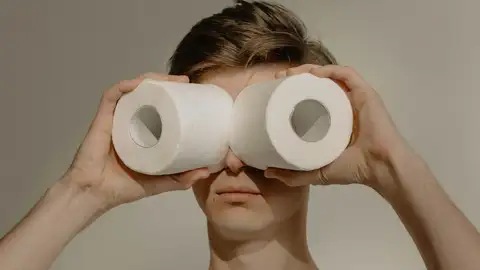 Un chico juega con dos rollos de papel higiénico Un chico juega con dos rollos de papel higiénico