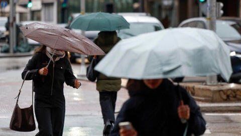 Varias personas pasean bajo la lluvia en Madrid 