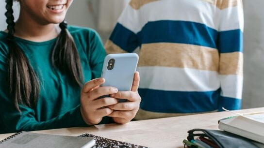 Unos ni&ntilde;os utilizan el tel&eacute;fono m&oacute;vil.