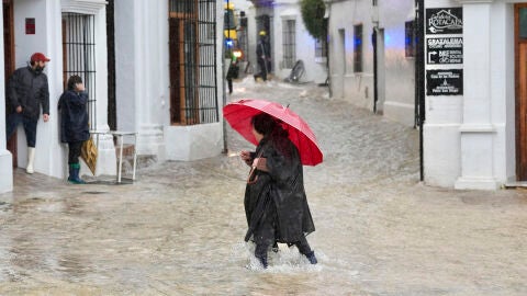 Una vecina de Grazalema (C&aacute;diz) camina por una calle inundada debido a las intensas lluvias