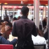 Camarero atendiendo clientes en una terraza en Madrid.