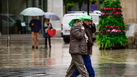 En la imagen varias personas caminan bajo la lluvia por las calles del centro de Castell&oacute;n.
