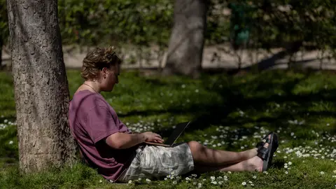 Una persona sentada en el césped de un parque en Madrid Cuando empieza la primavera: este el pronóstico del tiempo para la nueva estación