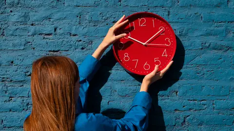Una mujer colgando un reloj en una pared Una mujer colgando un reloj en una pared