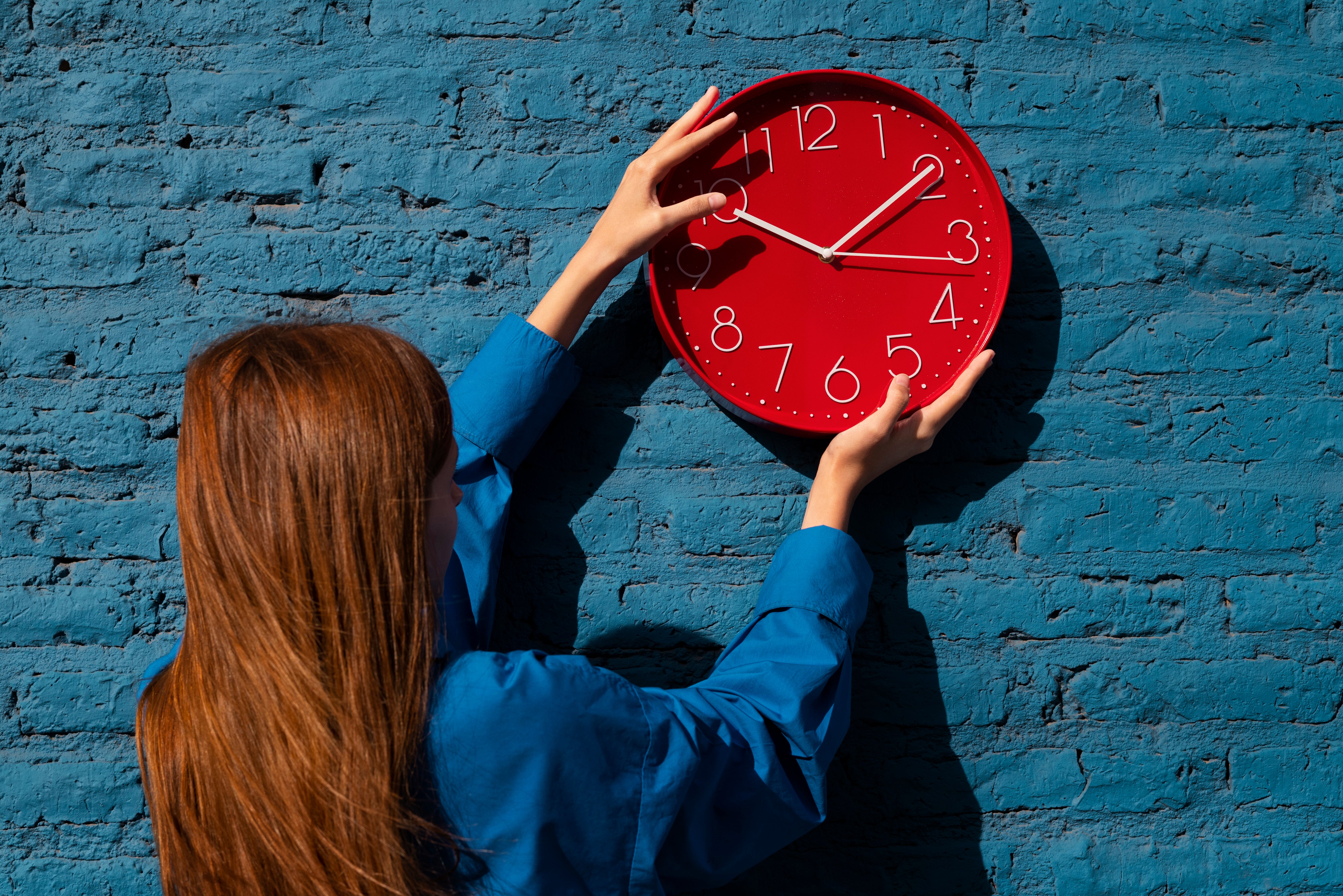 Una mujer colgando un reloj en una pared Una mujer colgando un reloj en una pared