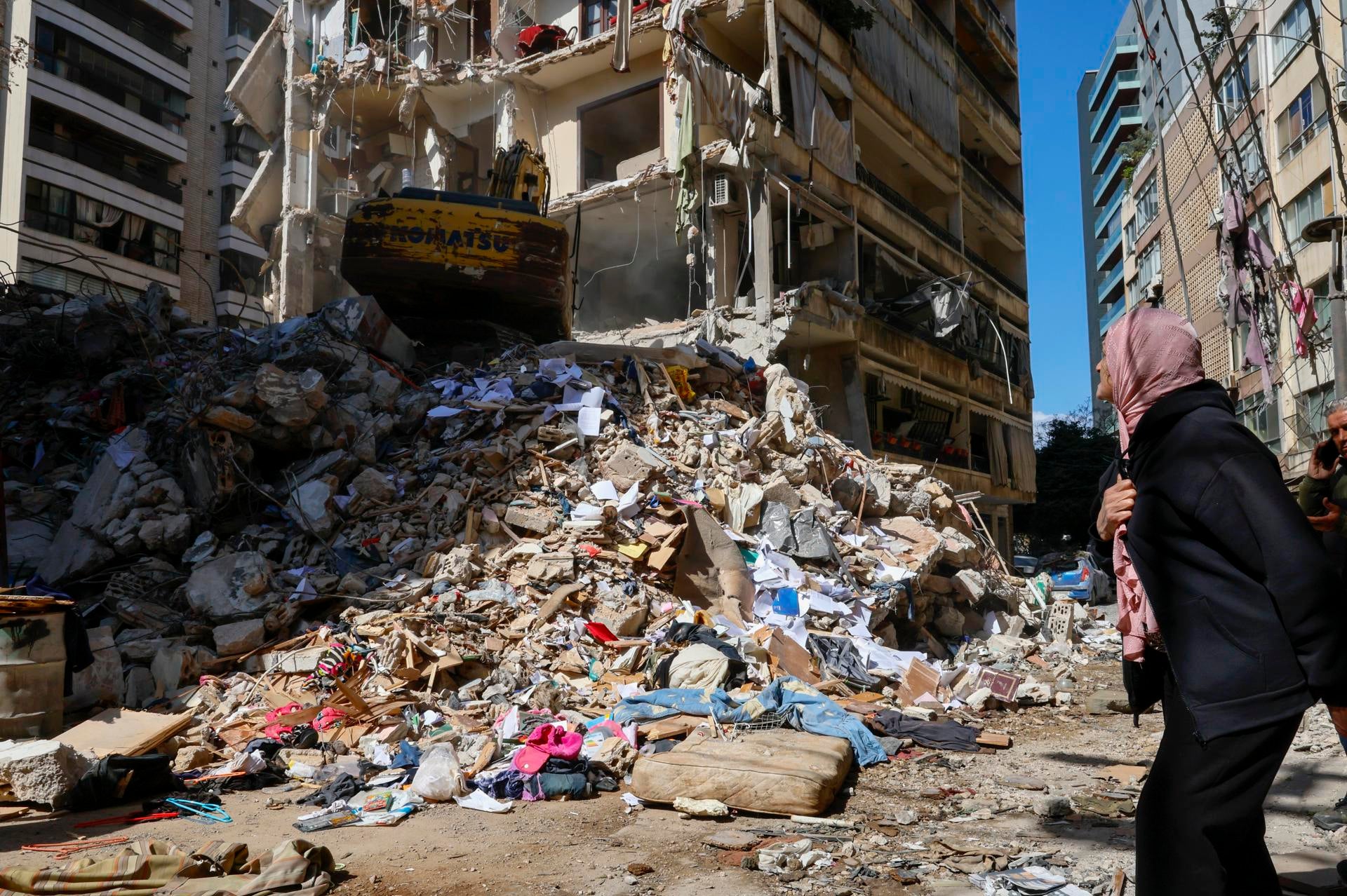 Una mujer observa cómo un bulldozer trata de limpiar un edificio destruido en un barrio de Beirut, en Líbano. Una mujer observa cómo un bulldozer trata de limpiar un edificio destruido en un barrio de Beirut, en Líbano.