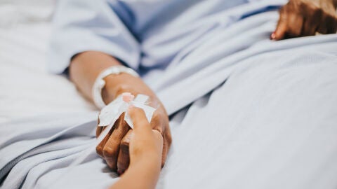Una persona le coge la mano a otra en un hospital 