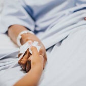 Una persona le coge la mano a otra en un hospital 