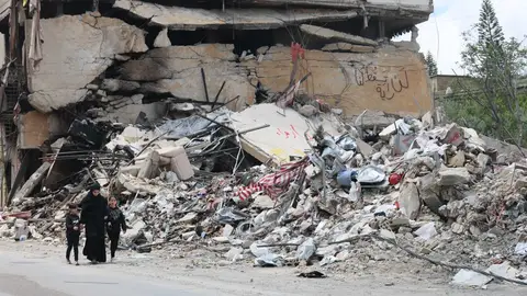 Personas caminan junto a los escombros de un edificio dañado por un ataque aéreo israelí en la aldea de Jibchit, al sur del Líbano, el 21 de abril de 2026. Personas caminan junto a los escombros de un edificio dañado por un ataque aéreo israelí en la aldea de Jibchit, al sur del Líbano, el 21 de abril de 2026.
