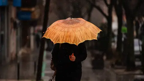 Una persona se protege de la lluvia con paraguas. Una persona se protege de la lluvia con paraguas.