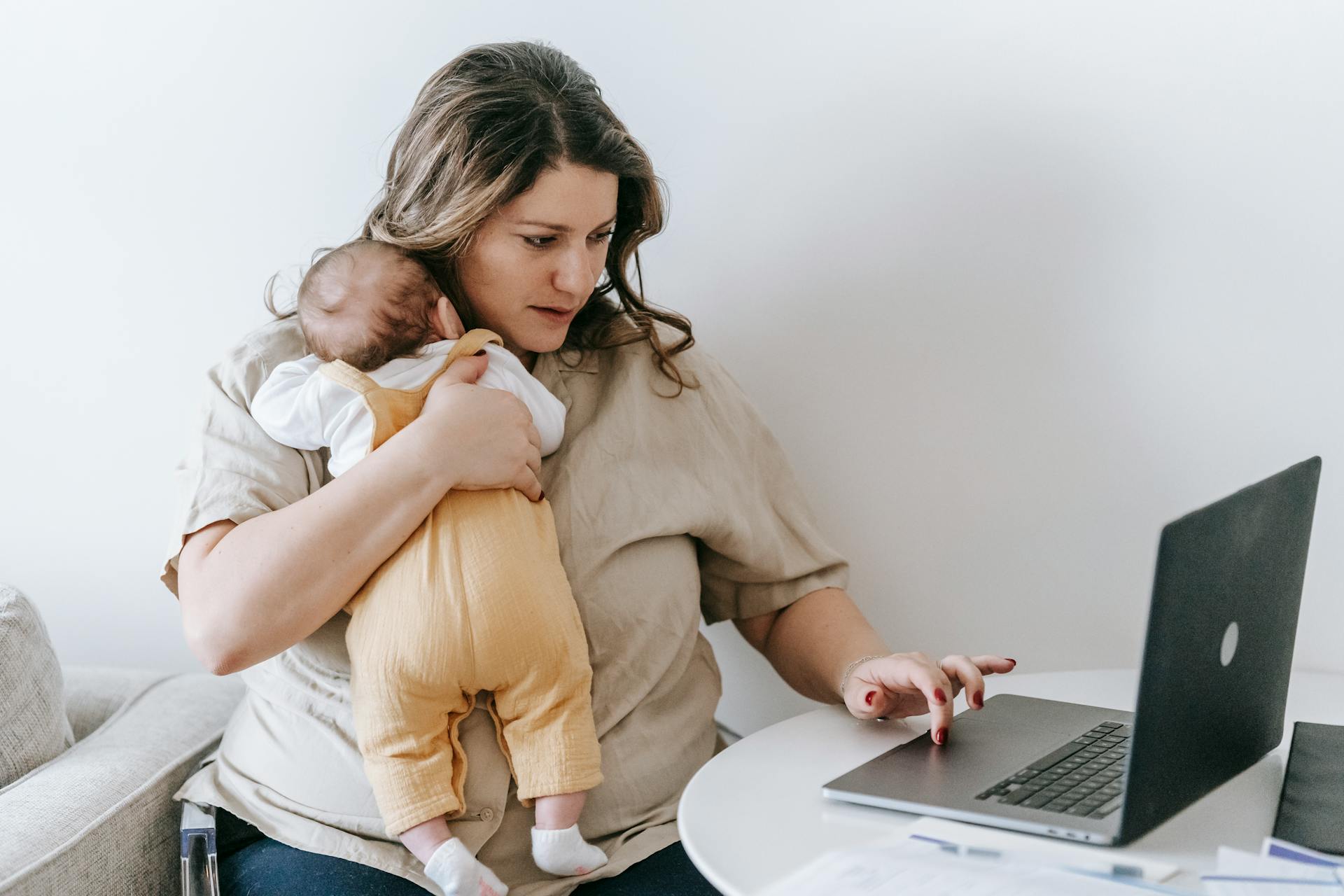 Imagen de archivo de una mujer trabajando con su bebé en brazos Imagen de archivo de una mujer trabajando con su bebé en brazos