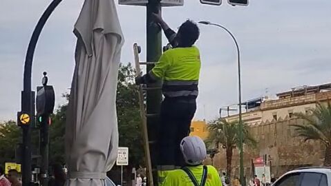 Operarios municipales desmontan una banderola de Por Andaluc&iacute;a