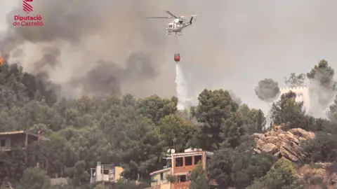 Una tregua meteorológica facilita la extinción del incendio antes de una cuarta ola de calor Un helicóptero de emergencias realiza una descarga de agua sobre el frente del incendio Vall D' Uixó