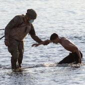 Un soldado del ejército ayuda a un inmigrante a su llegada a la playa de El Tarajal en Ceuta.