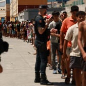 Migrantes esperan en fila para recoger comida en Ceuta.