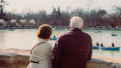 Pareja de ancianos disfrutando de una vista pacífica de barcos en un estanque del parque Pareja de ancianos disfrutando de una vista pacífica de barcos en un estanque del parque