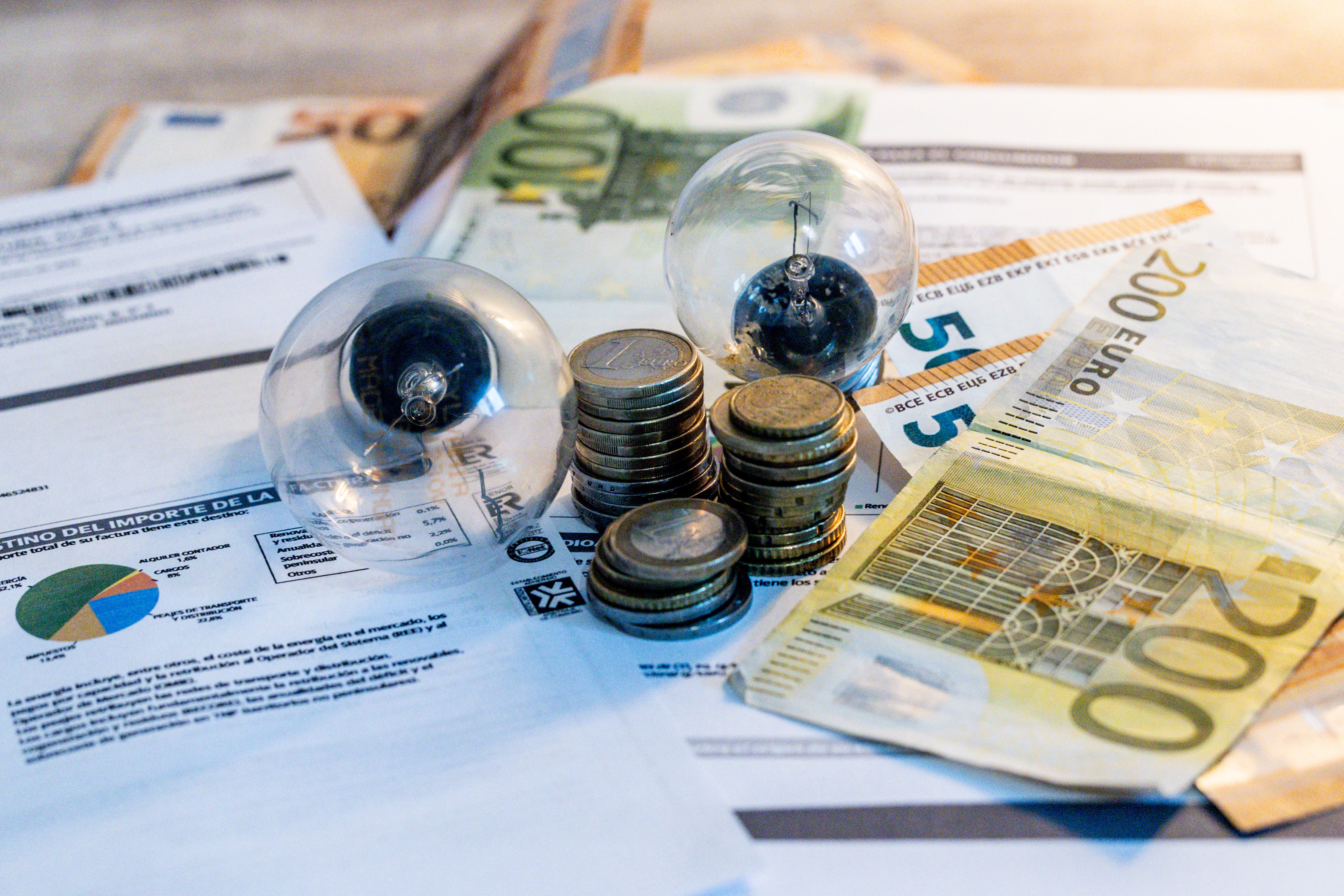 Dos bombillas sobre billetes, monedas y facturas Dos bombillas sobre billetes, monedas y facturas