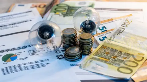 Dos bombillas sobre billetes, monedas y facturas Dos bombillas sobre billetes, monedas y facturas/ Ricardo Rubio / Europa Press
