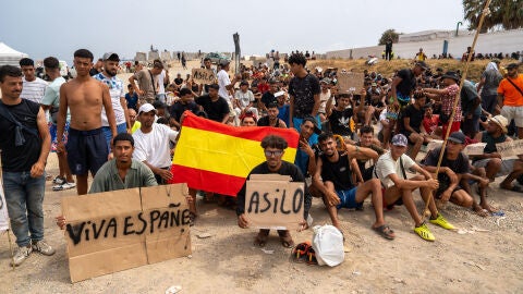 Un grupo de migrantes concentrados para solicitar asilo este domingo en la playa del trampolín de Ceuta. Un grupo de migrantes concentrados para solicitar asilo este domingo en la playa del trampolín de Ceuta.