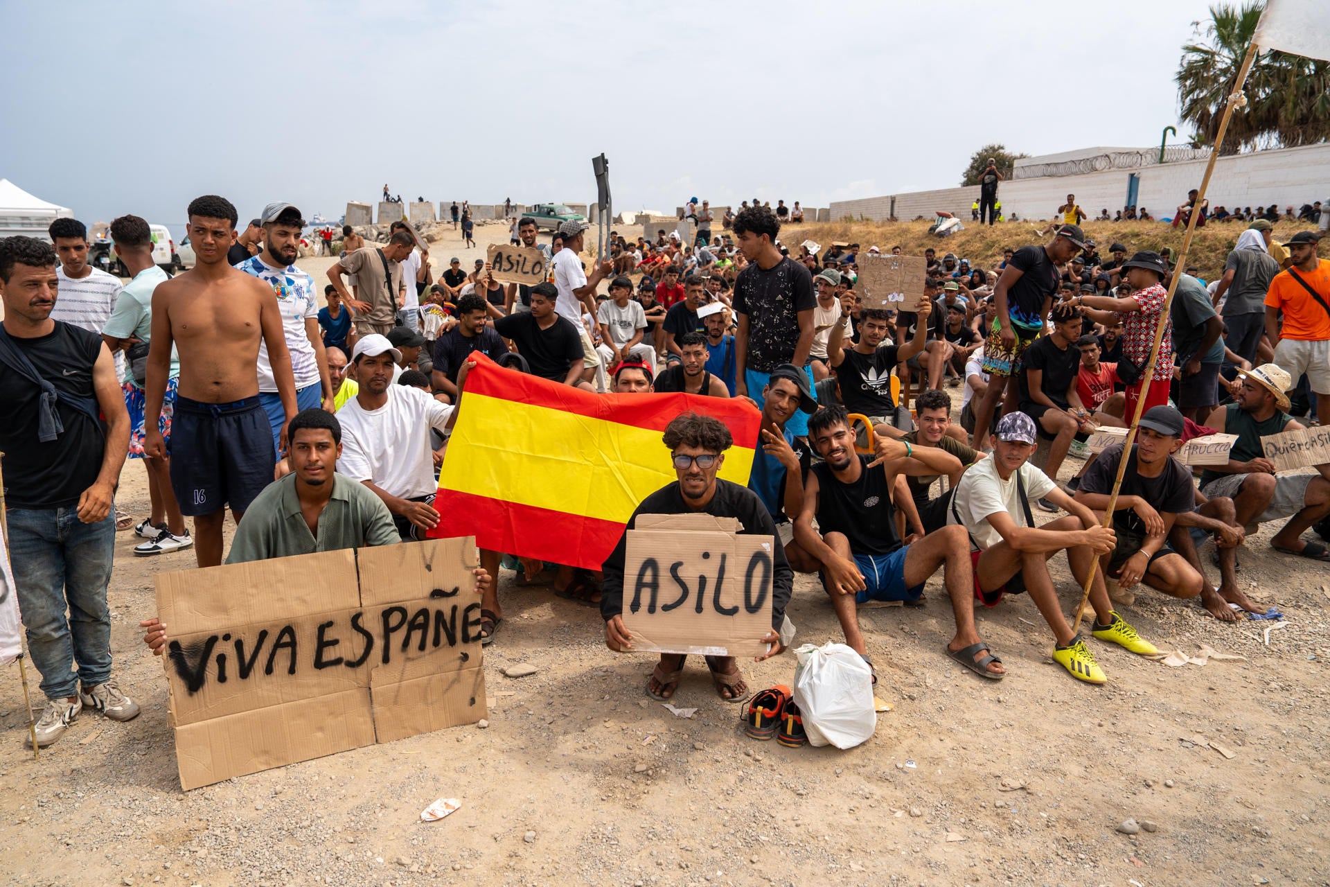 Un grupo de migrantes concentrados para solicitar asilo este domingo en la playa del trampolín de Ceuta. Un grupo de migrantes concentrados para solicitar asilo este domingo en la playa del trampolín de Ceuta.
