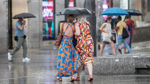 People cover themselves from rain with umbrellas during a summer storm coinciding with the second heat wave of the summer. People cover themselves from rain with umbrellas during a summer storm coinciding with the second heat wave of the summer.