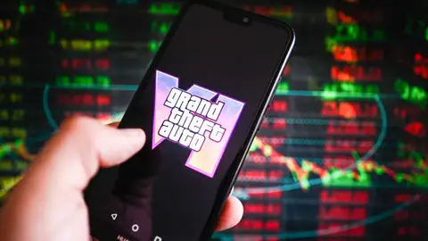 En esta imagen ilustrativa, se muestra el logotipo de Grand Theft Auto (GTA) VI en un teléfono inteligente, con porcentajes bursátiles de fondo. En esta imagen ilustrativa, se muestra el logotipo de Grand Theft Auto (GTA) VI en un teléfono inteligente, con porcentajes bursátiles de fondo.