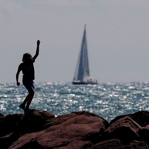 Archivo. Un niño corre por el espigón de una playa.