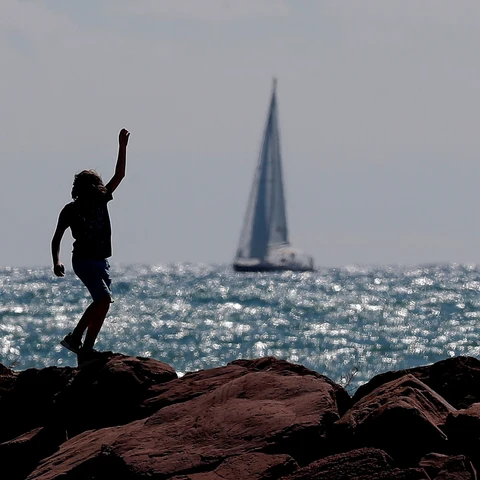 Archivo. Un niño corre por el espigón de una playa.