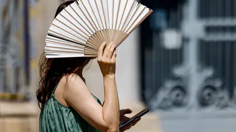 Una mujer se protege del intenso calor con un abanico. Una mujer se protege del intenso calor con un abanico.
