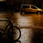 Coches circulan por una calle inundada tras las fuertes lluvias caídas en Valencia, este miércoles.