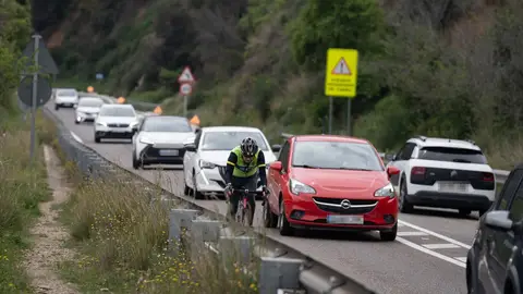 Una carretera de Cataluña en la que hay multitud de coches y un ciclista por el arcén Una carretera de Cataluña en la que hay multitud de coches y un ciclista por el arcén