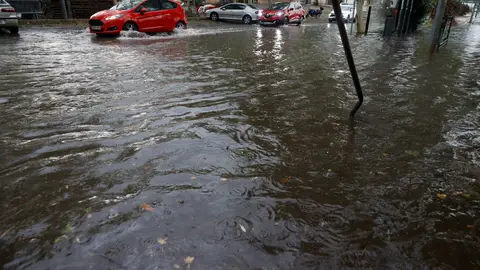 Varios vehículos circulan por una calle inundada a causa de la tormenta. Varios vehículos circulan por una calle inundada a causa de la tormenta.
