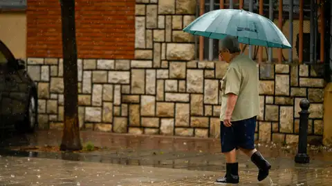 Una persona se protege de la lluvia con un paraguas Una persona se protege de la lluvia con un paraguas
