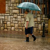 Una persona se protege de la lluvia con un paraguas Una persona se protege de la lluvia con un paraguas