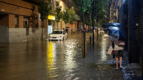 Imagen de archivo de una mujer andando en mitad de una calle inundada por las lluvias en el barrio de Bellvitge en L'Hospitalet de Llobregat (Barcelona)
