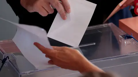 Una persona introduciendo su papeleta en una urna Una persona introduciendo su papeleta en una urna