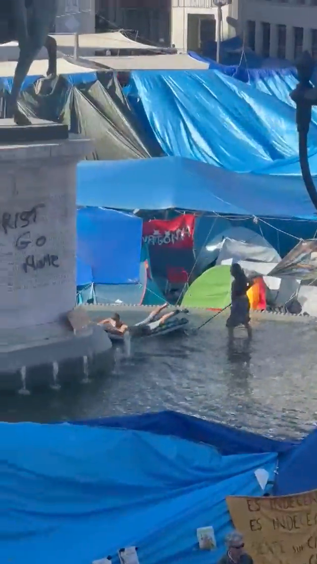 Los acampados de Sol utilizan la fuente de la estatua de Carlos III como piscina para bañarse con colchonetas Los acampados de Sol utilizan la fuente de la estatua de Carlos III como piscina para bañarse con colchonetas