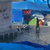 Los acampados de Sol utilizan la fuente de la estatua de Carlos III como piscina para bañarse con colchonetas