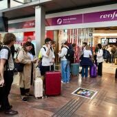 Varios pasajeros haciendo cola frente a Renfe para cancelar sus billetes